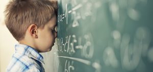 frustrated boy with head on chalkboard